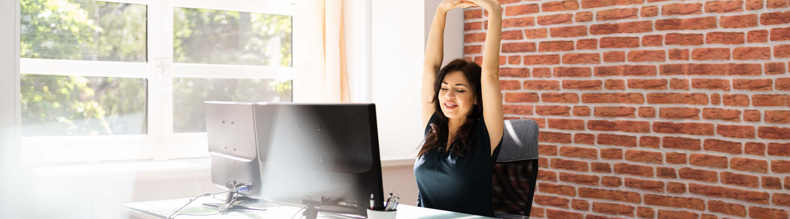 Frau sitzt im Büro und stretcht ihre Arme
